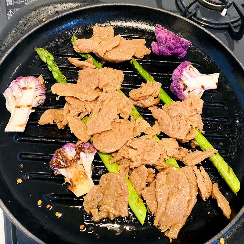 Añade la carne vegetal Shogayaki a los espárragos y la coliflor.