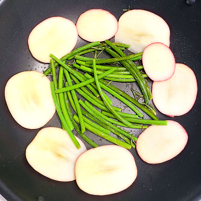 Add the sliced apple to the pan with the green beans and turn on the heat.