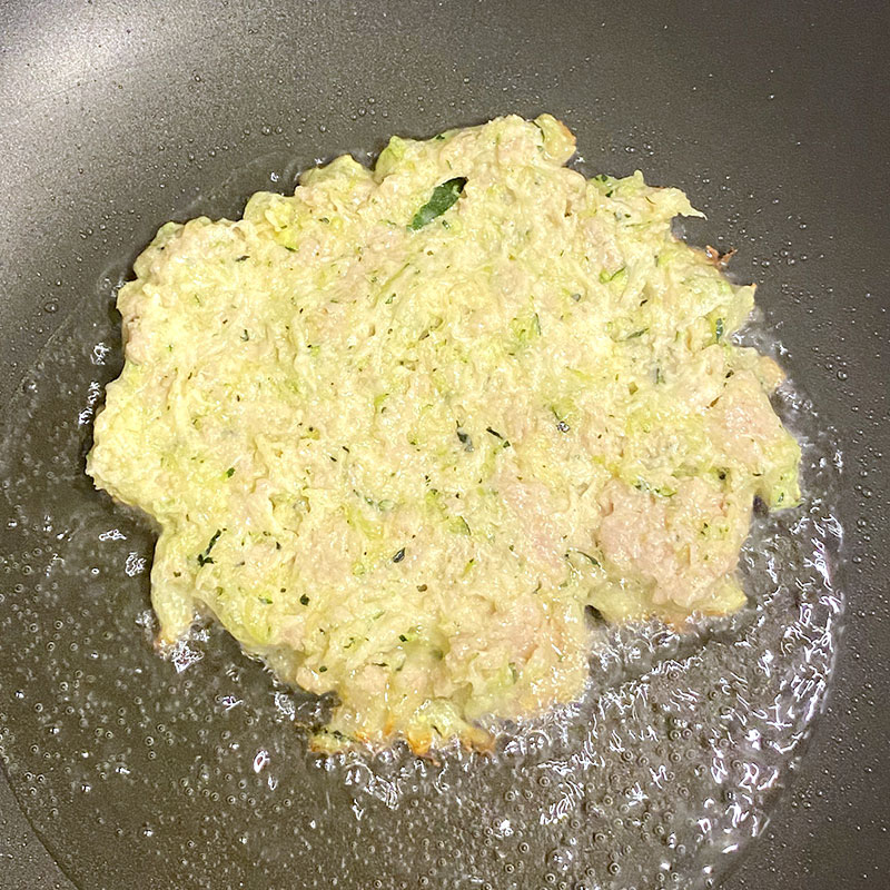 Drop about 2-3 tablespoons of the potato - zucchini mix onto the heated vegetable oil. And flatten it to make a pancake.