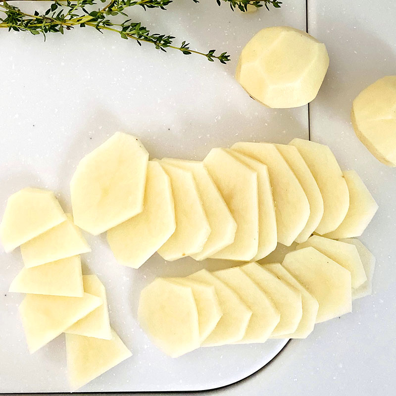 Pela y corta las patatas en rodajas de unos 0,5 cm de grosor. Luego corta las rodajas por la mitad.