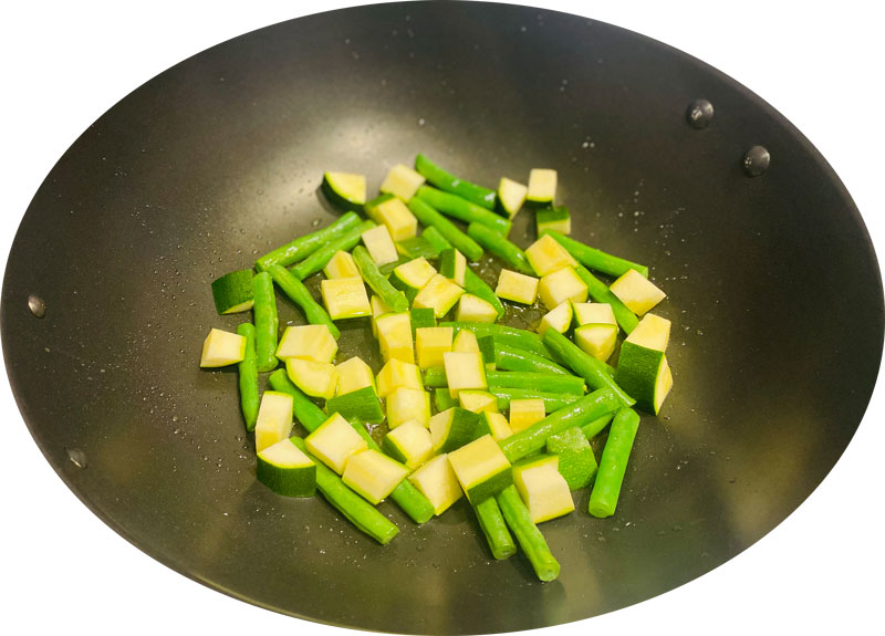 Dice the zucchini and halve the green beans. Fry them over a low heat for about 10 min, covered.